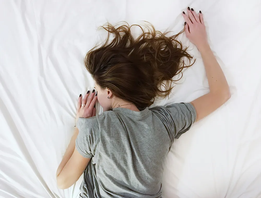 Woman lying down in bed facing down